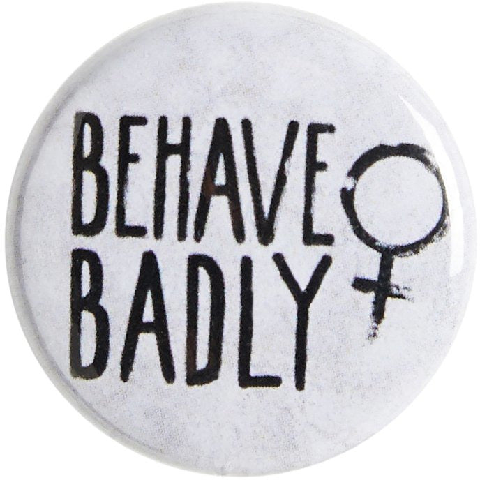 White pin badge with Behave Badly motto and female symbol. From the Rising Tide exhibition at Cambridge University Library, brought to you by CuratingCambridge.com