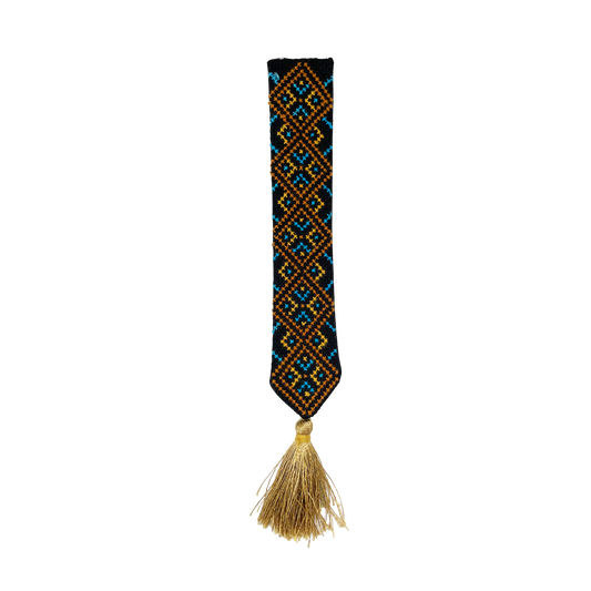 Decorative bookmark with an embroidered geometric pattern and gold tassel on a black background
