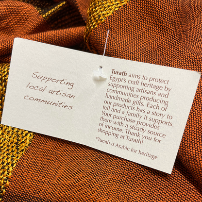 Textile with a Turath tag on an orange fabric background