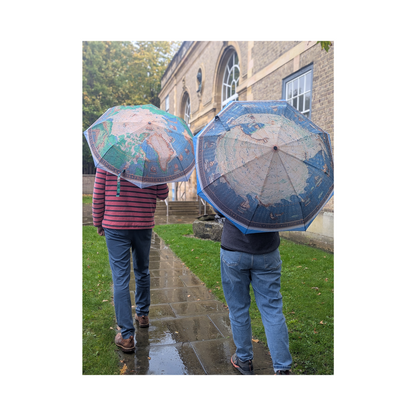 Two people holding world map umbrellas in a park setting.
