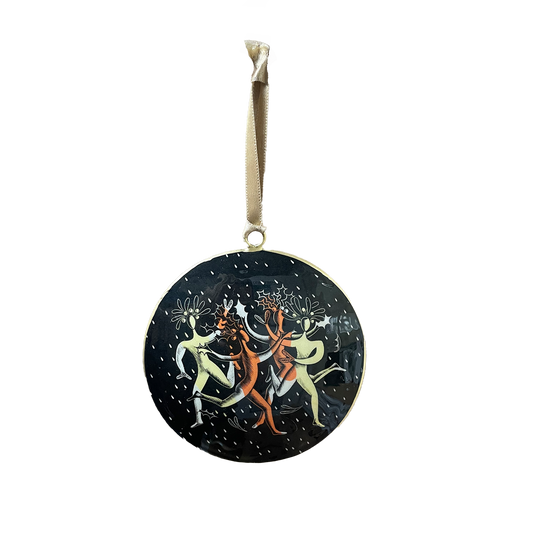 Decorative circular Christmas ornament with dancing figures on a black background, hanging from a pale gold satin ribbon.