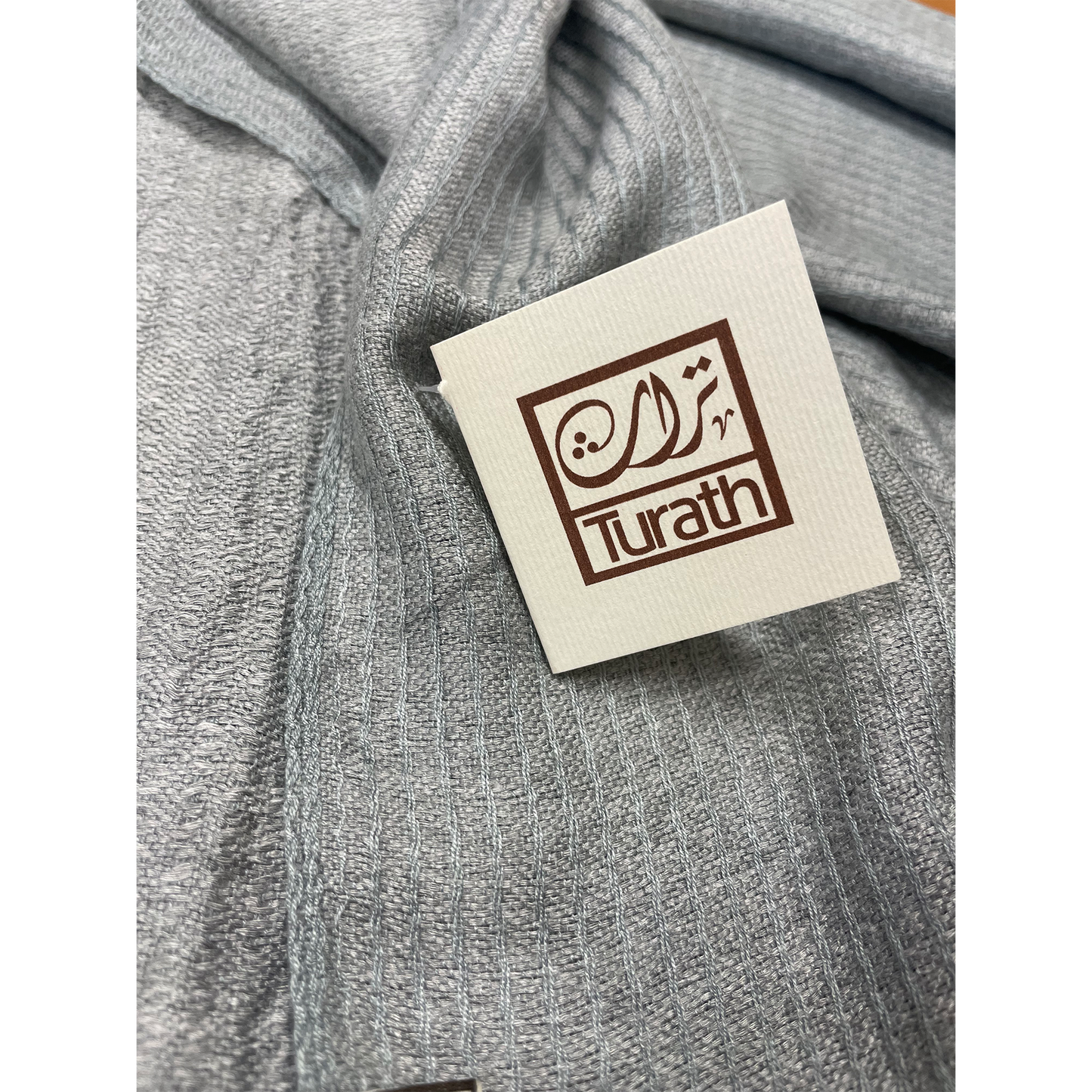 Gray fabric with a Turath label on a white background