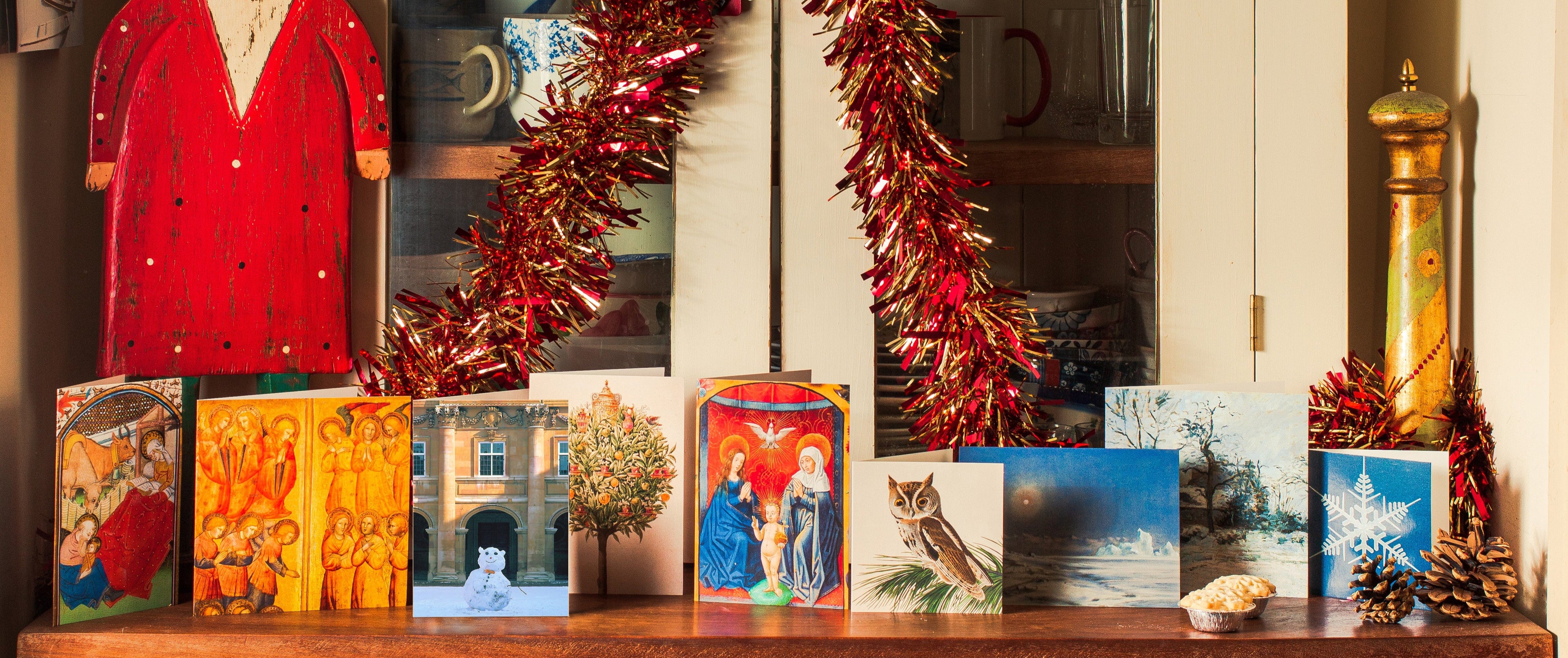 Decorative shelf with Christmas decorations, including a red tinsel wreath and greeting cards.