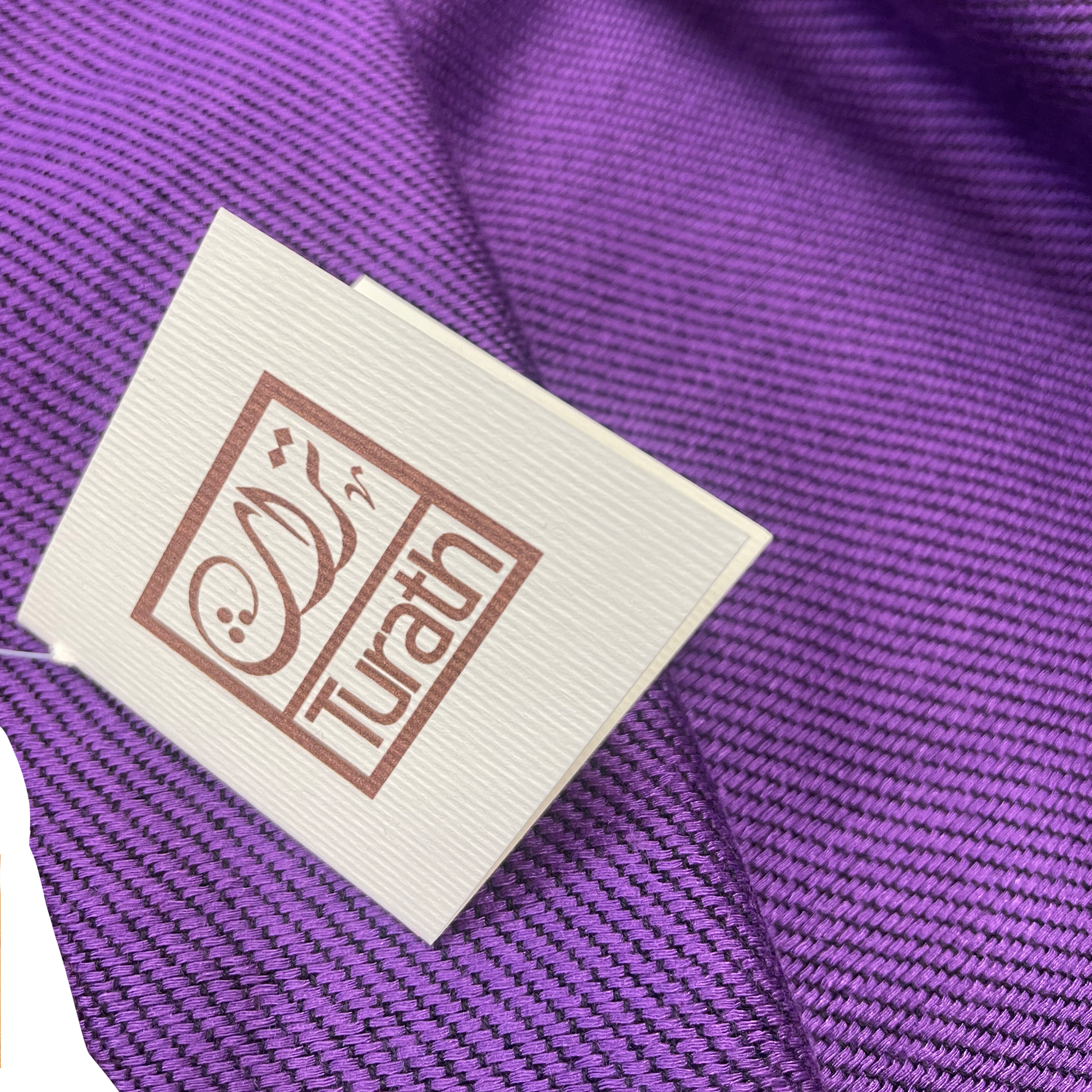 Label with 'Turath' branding on a purple fabric background