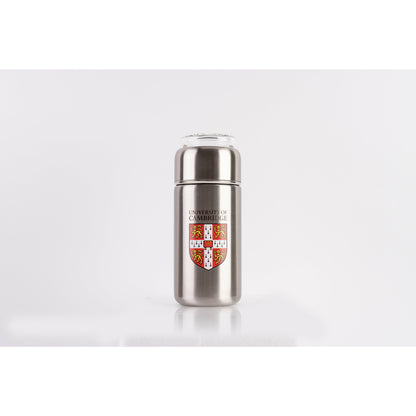Tea infuser with clear glass lid, brushed steel/silver colour. Decorated with University of Cambridge shield on the front.