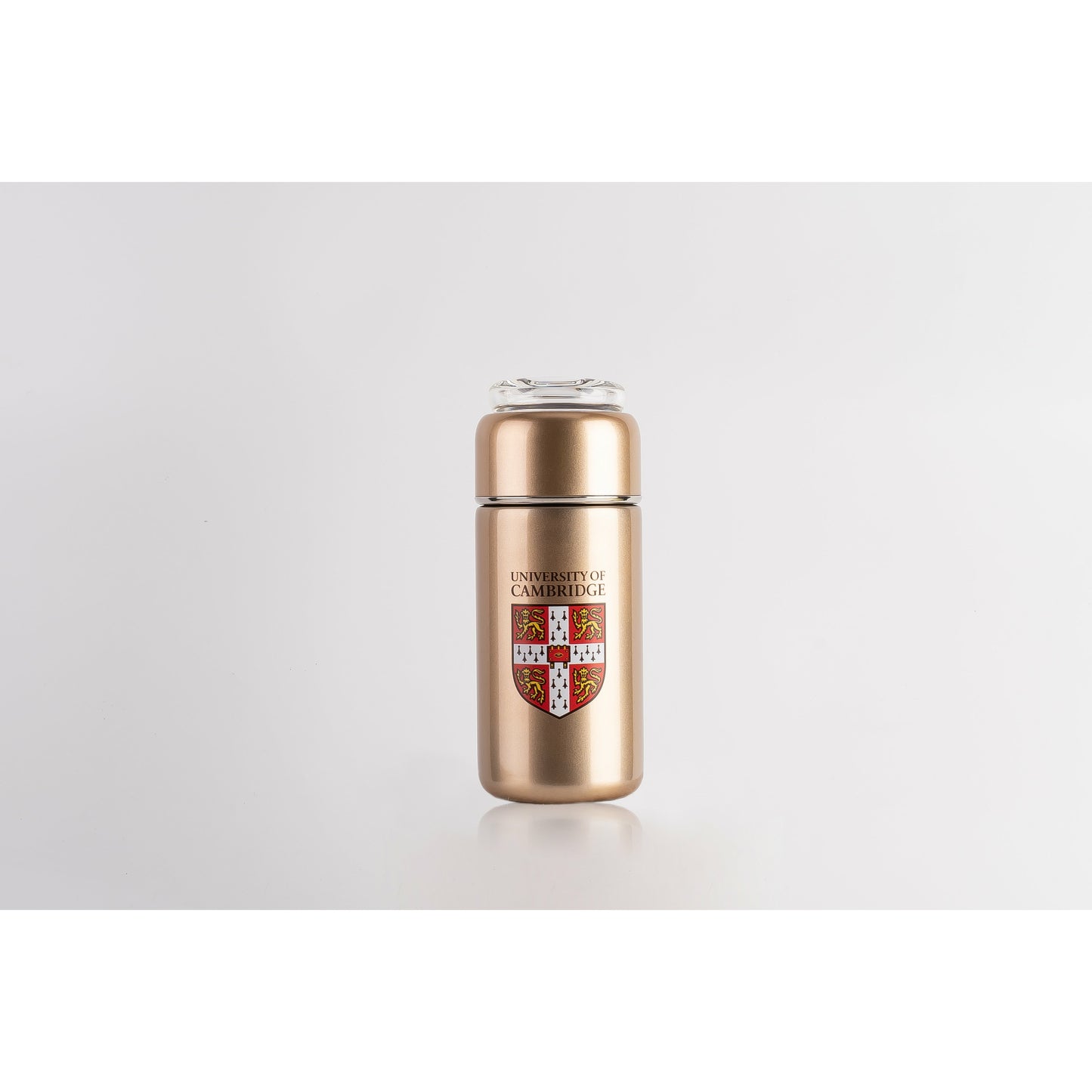 Gold tea infuser with clear glass top, and decorated with University of Cambridge shield.